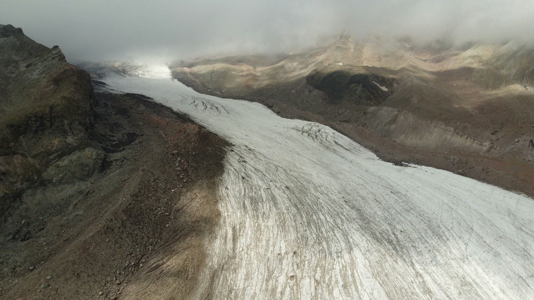 Aerial view of a glacier flowing through a mountain landscape